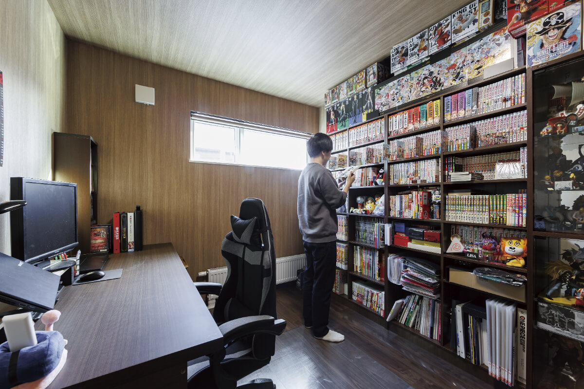 壁一面の漫画やフィギュアなど、趣味のグッズがずらりと並ぶシェルフが印象的なこちらの書斎。